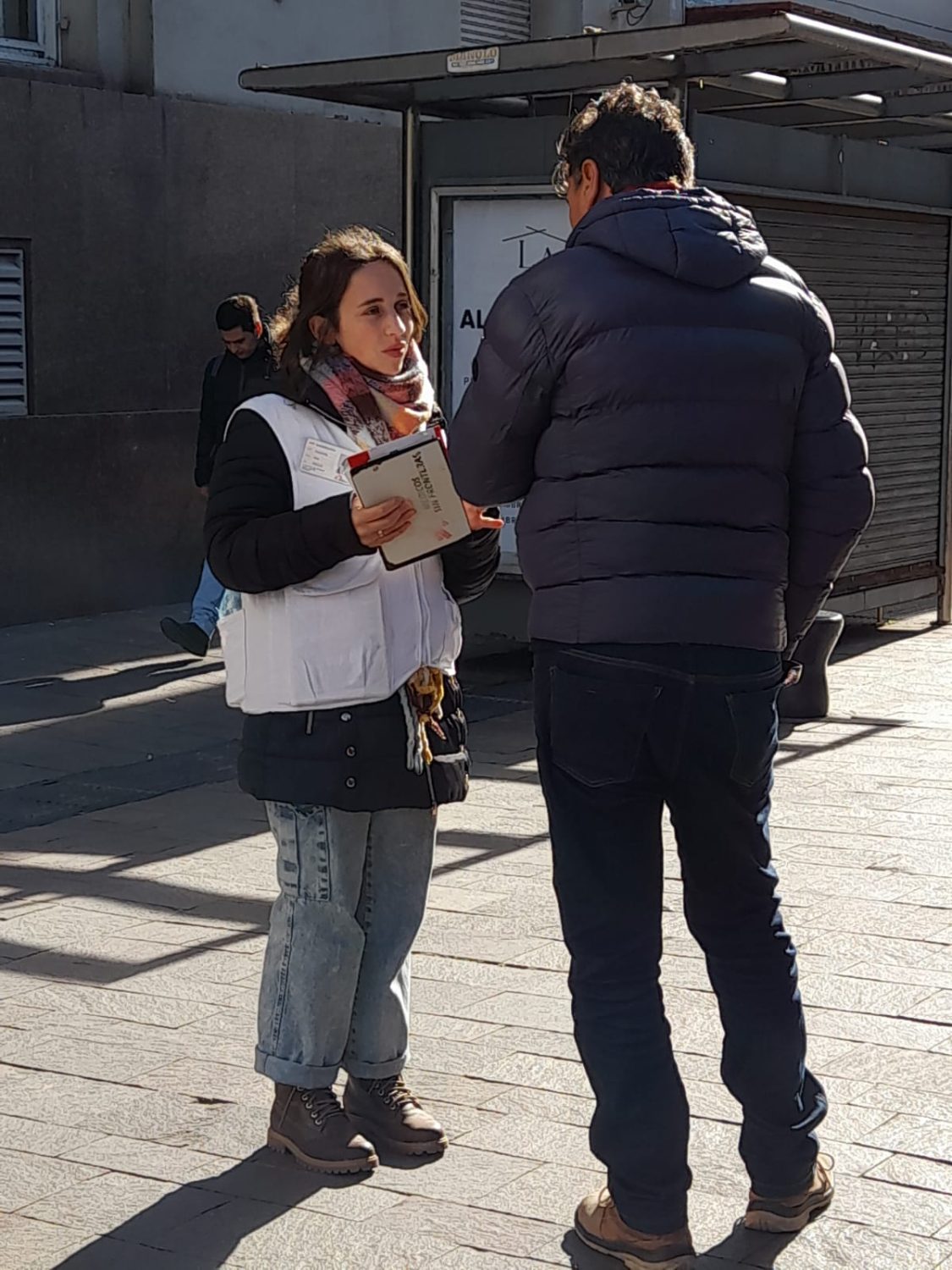 Trabajadora de Médicos Sin Fronteras hablando con un hombre en calle céntrica de Pergamino.