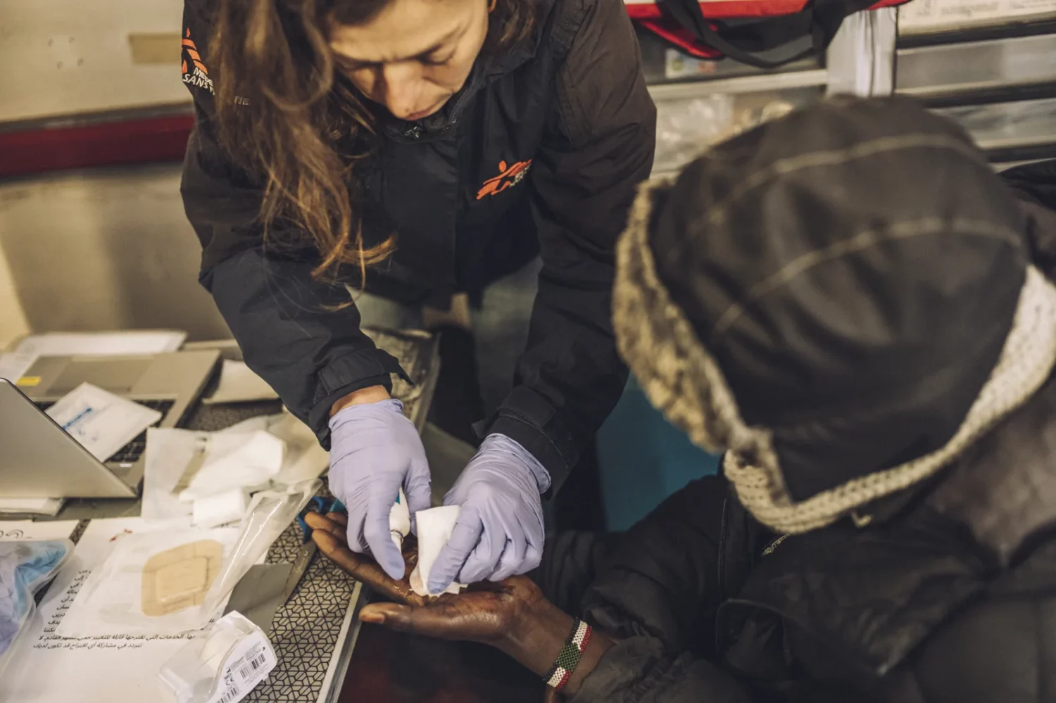 Una enfermera de MSF cura la mano de un joven migrante sudanés en Calais. © Stéphane Lavoué.